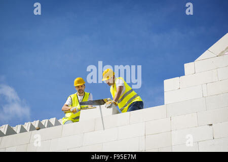 Les constructeurs travaillent sur le haut de la construction de maisons. Banque D'Images