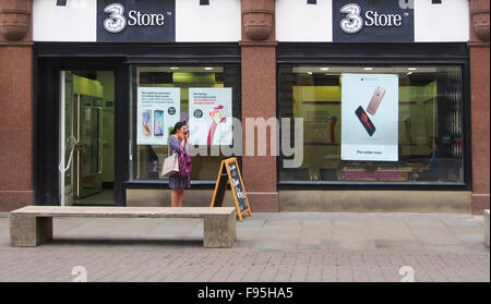 Femme faisant un appel sur son téléphone portable, alors que se tient en dehors de la boutique 3 boutique de téléphonie mobile à St Anne's Square, Manchester. Banque D'Images