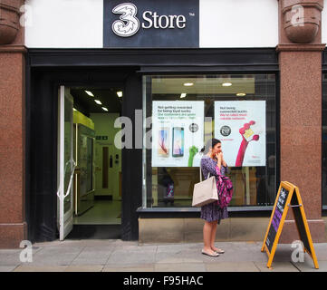 Femme faisant un appel sur son téléphone portable, alors que se tient en dehors de la boutique 3 boutique de téléphonie mobile à St Anne's Square, Manchester. Banque D'Images