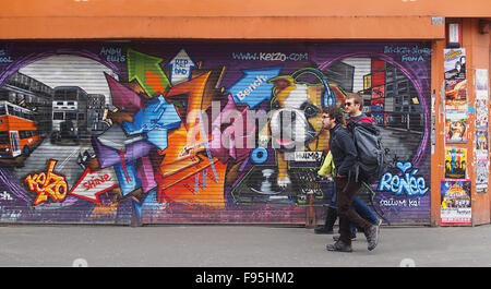 3 jeunes hommes devant certains street art sur volets dans Stevenson Square, Rue du levier, le centre-ville de Manchester, au Royaume-Uni. Banque D'Images