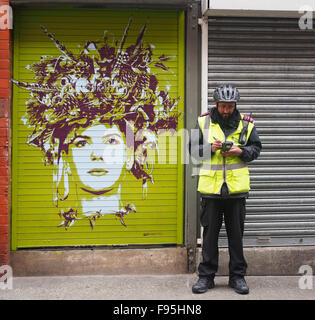 Street Art Par Tankpetrol sur un obturateur sur Tib Street dans le quartier nord du centre-ville de Manchester, UK avec un gardien de la circulation Banque D'Images