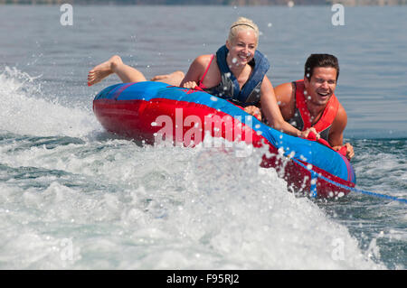 Brett et Kali rire comme ils tenir solidement sur le tube car il est tiré de l'arrière du bateau, sur le lac Kalamalka, C.-B. Banque D'Images