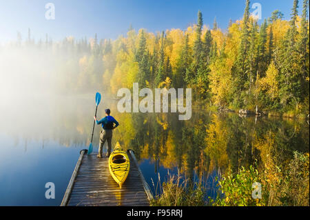 Un homme et un kayak à quai, Dickens Lake, Nord de la Saskatchewan, Canada Banque D'Images