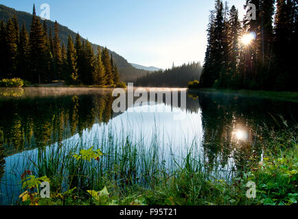 La fin de l'été le soleil se lève sur le lac de la foudre à Manning Park, BC et fournit une réflexion spectaculaire. Banque D'Images