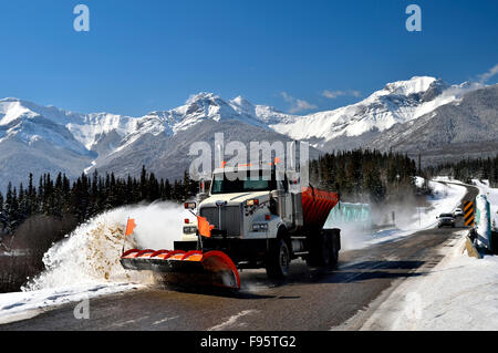 Un camion labourant la neige sur le bord de la route par un beau jour de l'hiver dans les montagnes rocheuses de l'Alberta Canada Banque D'Images