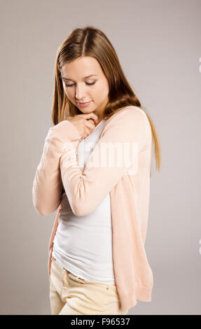 Belle jeune femme posant en studio sur un fond gris Banque D'Images