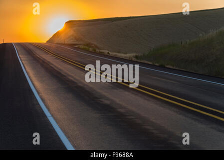 Lever de soleil derrière une colline au-dessus d'une route près de la ville de Colfax, Washington, États-Unis Banque D'Images