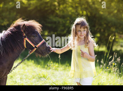 Portrait de jeune fille tlittle s'amusant à l'extérieur, de l'alimentation campagne pony Banque D'Images