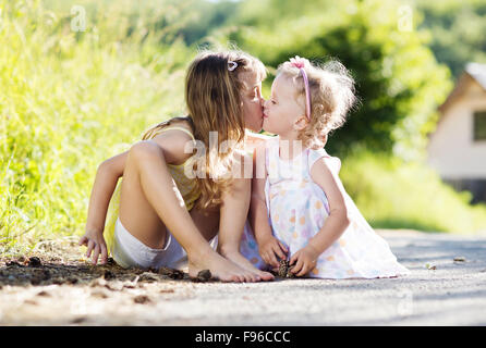 Deux mignonnes petites sœurs sittting et baisers dans la nature Banque D'Images