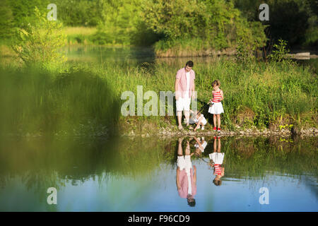 Heureux jeune père de la pêche sur le lac avec ses petites filles, reflétant dans l'eau Banque D'Images