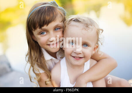 Deux mignonnes petites sœurs sittting par le lac Banque D'Images