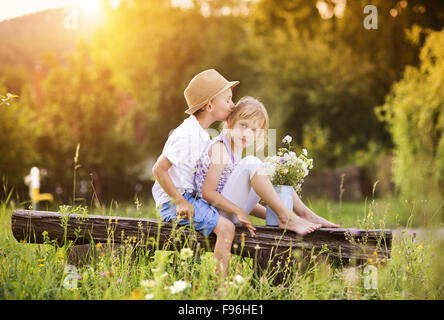 Cute boy and girl dans l'amour. Ils assis sur un banc au coucher du soleil. Banque D'Images