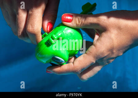 Jouet grenouille en plastique horlogerie, jouet grenouille dans les mains de femme Banque D'Images
