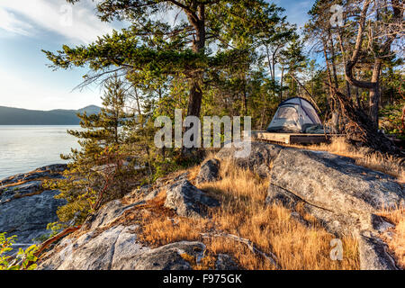 Le soleil se couche sur la tente de la kayakiste sur l'île ouest Curme dans le parc marin de Desolation Sound, en Colombie-Britannique, Canada. Banque D'Images