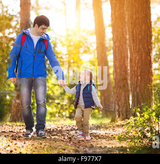Père et fils pendant la marche les activités de randonnée en forêt d'automne au coucher du soleil Banque D'Images