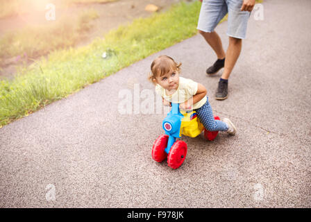 Père avec sa petite fille sur moto en vert sunny park Banque D'Images