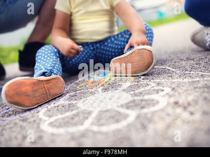 Close up de petite fille et son père dessiner avec les craies sur le trottoir Banque D'Images