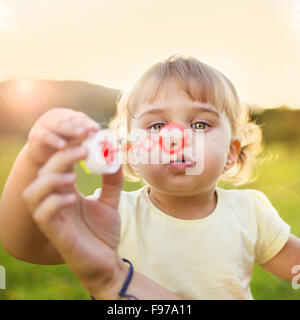 Happy little girl blowing bubbles en été la nature Banque D'Images