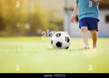 Close-up of little boy playing football sur terrain de football Banque D'Images