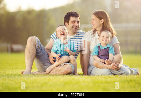 Happy Family est relaxant et assis sur un terrain de football Banque D'Images