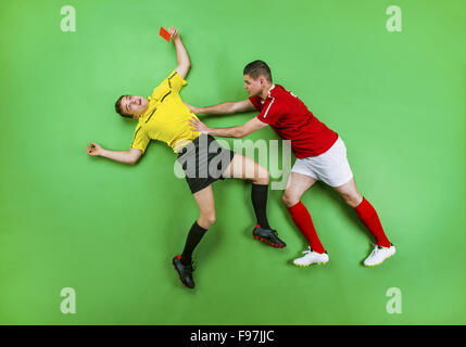 Carton rouge à l'arbitre de donner un joueur de football. Studio shot sur un fond vert. Banque D'Images