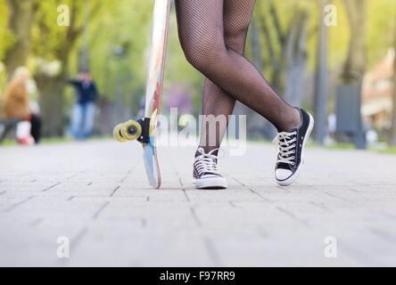 Close-up of legs of teenage girl holding skateboard Banque D'Images