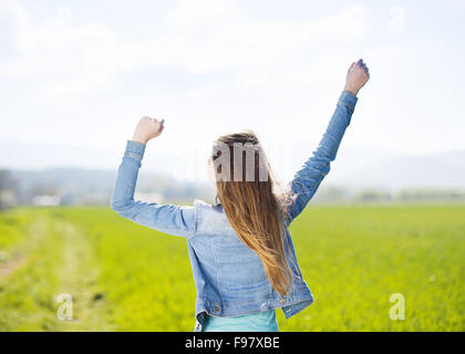 Jeune fille en bleu jeans jacket profiter de temps libre dans le champ vert Banque D'Images