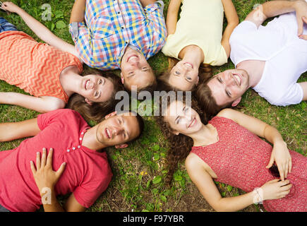 Groupe de jeunes gens s'amuser dans le parc, allongé sur l'herbe Banque D'Images