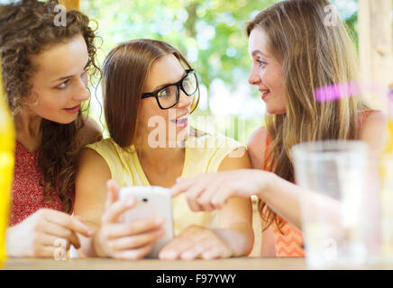 Trois belles filles boire et s'amuser avec le smartphone dans le jardin pub Banque D'Images