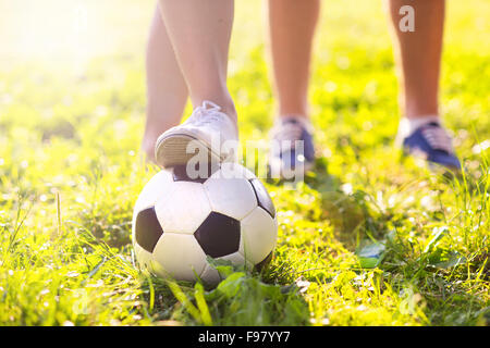 Close up de pieds et balle de football sur la pelouse de l'herbe verte Banque D'Images