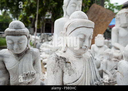 MANDALAY, Myanmar — les artisans locaux entreprennent le travail poussiéreux et épouvantable de sculpter des statues du Bouddha en marbre. Le bouddhisme étant la religion dominante au Myanmar, il y a une demande considérable pour les statues, avec des clients capables de choisir parmi une myriade de poses, tailles et styles. Les artisans sont regroupés dans une rue du quartier Chanmyathazi de Mandalay, près de la pagode Mahamuni. Banque D'Images