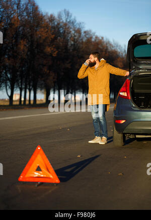 L'homme examinant pilote automobile voitures endommagées après la rupture Banque D'Images