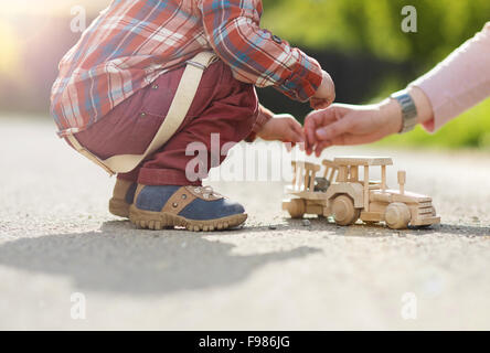 Close-up de petit Garçon jouant avec tracteur en bois sur l'extérieur de la chaussée Banque D'Images