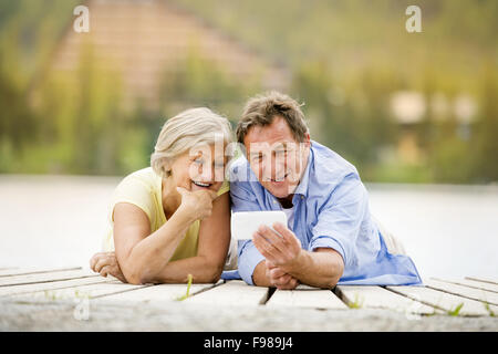 Senior couple couché et en tenant sur selfies pier Banque D'Images