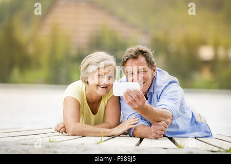 Senior couple couché et en tenant sur selfies pier Banque D'Images