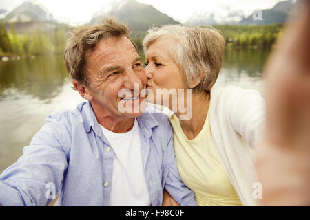 Couple sur un bateau avec montagnes en arrière-plan en tenant selfies Banque D'Images