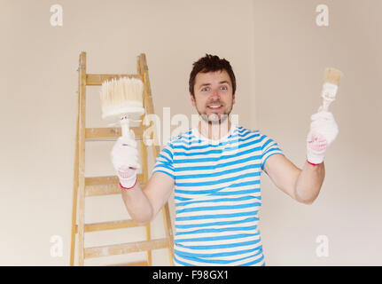 Happy smiling man peindre les murs de la nouvelle maison avec paintbrush Banque D'Images