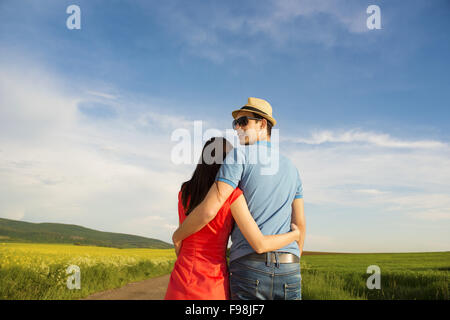 Happy young couple in love hugging sur route de campagne à côté de la champ de colza Banque D'Images