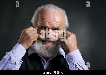 Portrait de vieux barbu, posant en studio sur fond noir Banque D'Images