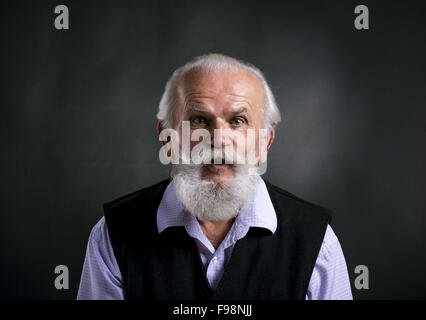 Portrait d'homme barbu vieux surpris, posant en studio sur fond noir Banque D'Images