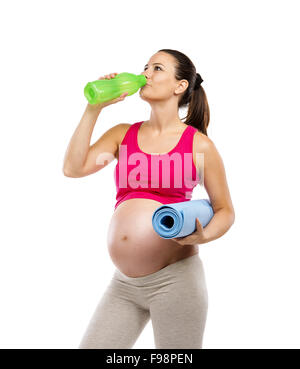 Studio Portrait of a beautiful young pregnant woman holding exercice de mat et de l'eau potable, isolé sur fond blanc Banque D'Images