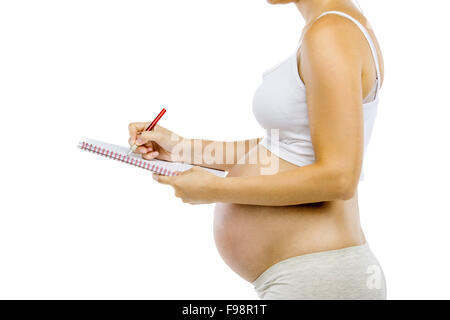 Studio portrait d'une femme enceinte avec méconnaissable carnet et un stylo isolé sur fond blanc Banque D'Images