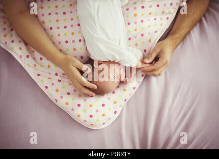 Cute baby girl sleeping in bed, les mains de ses parents lui touchant Banque D'Images