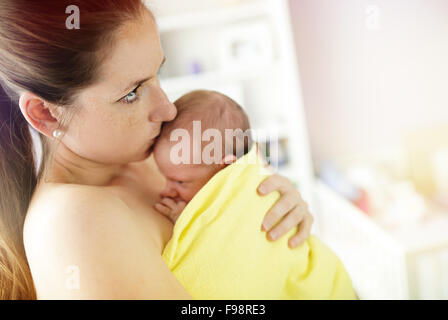 Jeune mère et l'embrassant holding newborn baby girl at home Banque D'Images