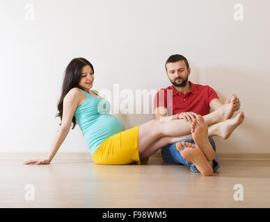 Jeune couple est assis sur le sol dans leur nouvelle maison vide. Femme est enceinte. Banque D'Images