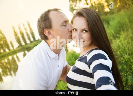 Happy young pregnant couple hugging in nature et prendre des selfies Banque D'Images