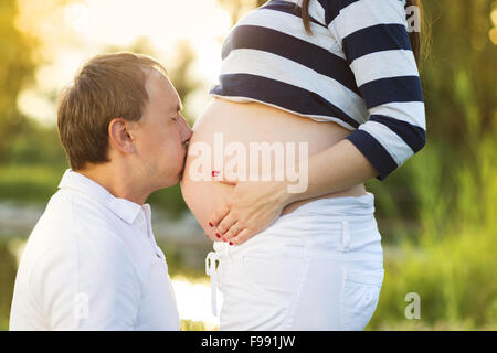 L'homme est kissing pregnant woman's belly dans la nature Banque D'Images