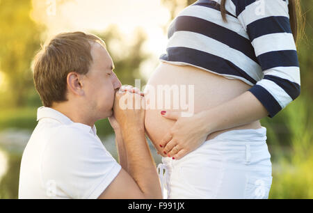 L'homme est kissing pregnant woman's belly dans la nature Banque D'Images