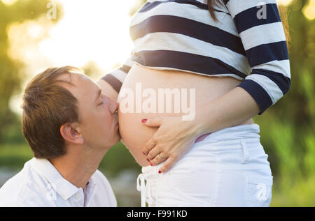 L'homme est kissing pregnant woman's belly dans la nature Banque D'Images