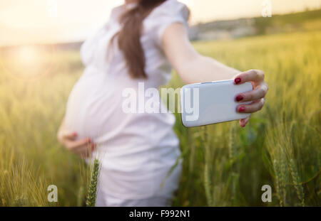 Jeune femme enceinte de prendre dans le domaine selfies Banque D'Images